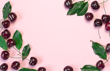 sweet cherry berries and green leaves on a pink background with space for text	