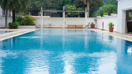 empty swimming pool with blue water in a residential area with green trees around it