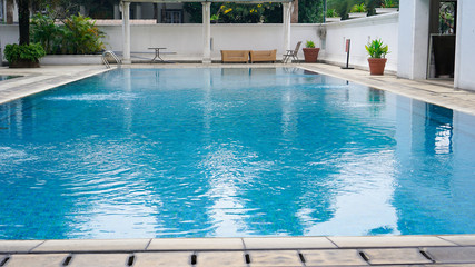 empty swimming pool with blue water in a residential area with green trees around it