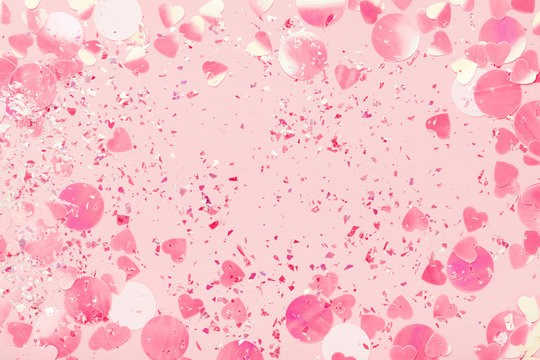 Confetti and sparkles on pink pastel background. Festive frame, holiday backdrop. Flat lay, copy space.