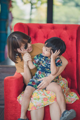 Mother and boy sitting laughing at the red sofa.