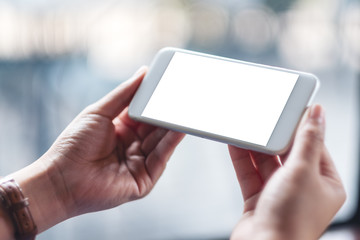 Mockup image of woman's hands holding white mobile phone with blank screen