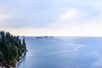 Cargo ships and boat in bay near shore in Vancouver, BC, Canada.