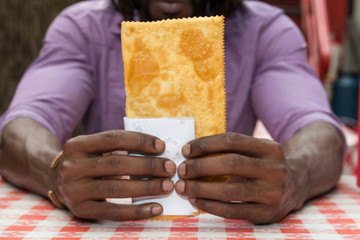 African american man showing brazilian snack known as Pastel - asian recipe.