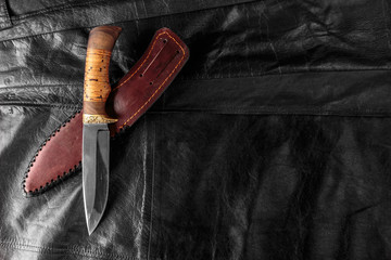 Hunting knife on black leather background