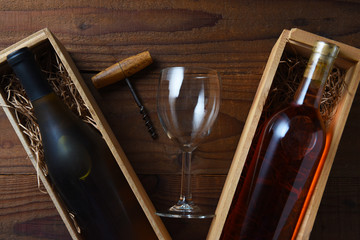 A bottle of Chardonnay and Rose Wine in boxes  on a rustic wood table with corkscrew and wineglass