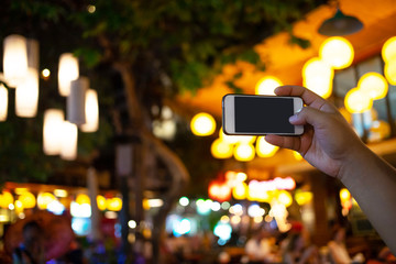 Hand holding smart phone with night light bokeh background