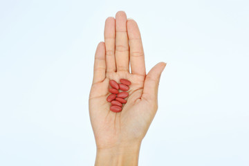 Close-up hand of a woman with some pills on white background