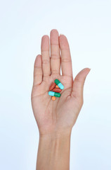 Close-up hand of a woman with some pills on white background