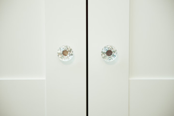 Two crystal handles on white wooden Cabinet doors