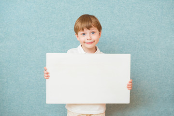 Young boy holding white blank board on blue background