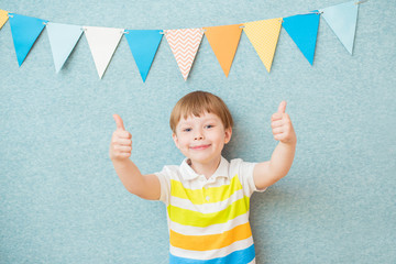 Portrait of a smiling boy is showing like on the blue background. The concept of children's holiday