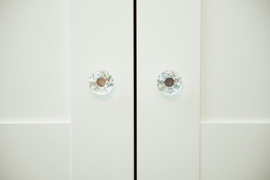Two crystal handles on white wooden Cabinet doors