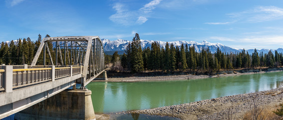 metal bridge over the river with green water in spring with mountains on the background.