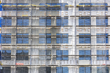 building facade under construction with scaffolding and protective net