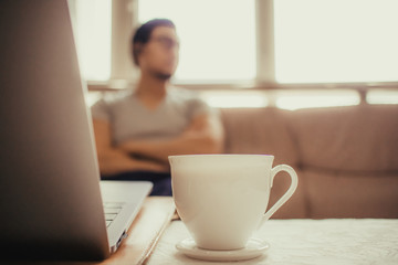 White cup of hot coffee on the table of a freelance man.