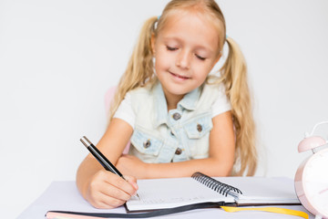 Back to school and happy time. Children holding pen and writting in notebook on white background. Kid making homework. Mockup, place for text, education concept