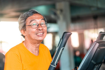 Happy Senior male is working out on fitness machine for elder healthy concept