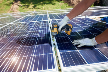 Using drill mounter istalling solar batteries on metallic carcass. Innovative high-tech exterior....