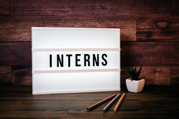 Interns. Text in lightbox. Wooden office table