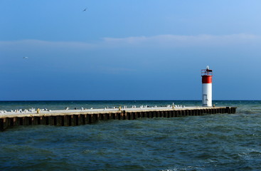 lighthouse and pier at sea, beautiful blue sky with birds