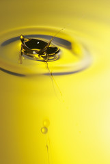 Golden yellow oil dropping and rippling over the abstract background