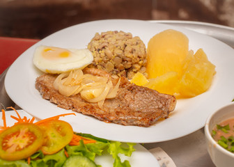 Refeição composta de bife acebolado, mandioca cozida, feijão tropeiro e ovo cozido.