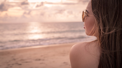 Fototapeta na wymiar Young woman with sunglass on the beach at Sunset time in Thailand.summer travel concept with copy space for your Design.