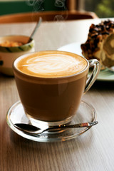 Hot latte and roll cake on a wooden table