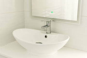 Chrome faucet, sink and washbasin. Modern white bathroom interior.