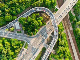 Photo from above of multi-level roads with traffic jams, green forest