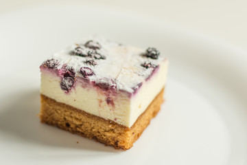 Cheesecake with fruits. A piece of cake with cream and soft cheese on white plate.