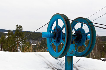 Rotating wheels of skiing drag lift on top of mountains slope, small ski resort