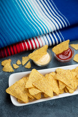 Plate of nachos with dipping sauces, vertical shot with mexican poncho in the background