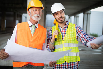 Confident team of architects and engineers working together on construction site
