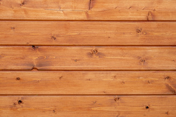 Fototapeta premium The wall is covered with wooden boards and covered with orange protective impregnation