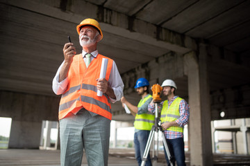 Team of architects and engineer in group on construciton site check documents and business workflow