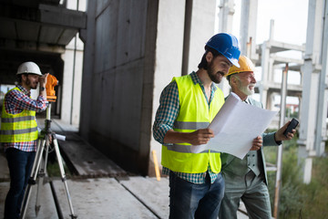 Team of architects and engineer in group on construciton site check documents and business workflow