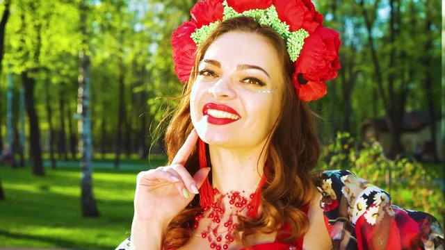 attractive young woman in folklore costume and flower circlet smiling at camera