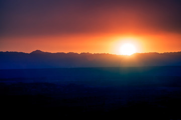 A warm sunset over the highway in a purple-orange color with mountains on the horizon