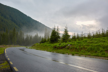 Naklejka premium Asphalt road into misty mountains