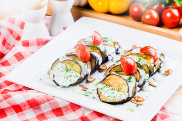 Grilled slices of eggplant and tomatoes in stack with spicy sauce
