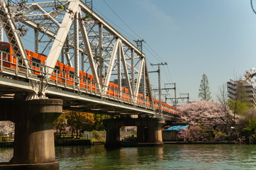 河川に架かる鉄橋とオレンジの鉄道と桜