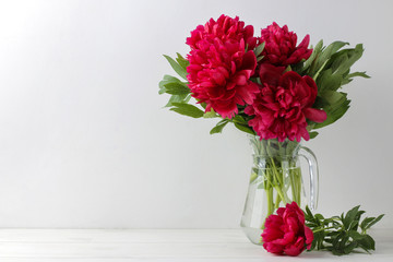 Beautiful bright pink flowers peonies in a jug on a light background. space for text