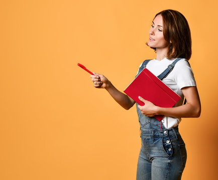 Pretty Young Beautiful Woman Standing, Writing, Take Notes, Holding Textbook Notebook Organizer In Hand And Pen