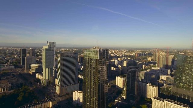 Aerial view of tall buildings and skyscrapers of the city of Warsaw, during the sunrise, summer morning. Financial office, business district. Reflection of the sun in glass skyscrapers. Shot on 4k.