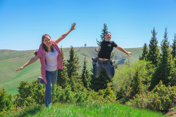 A woman and a man are jumping for joy in a picturesque place