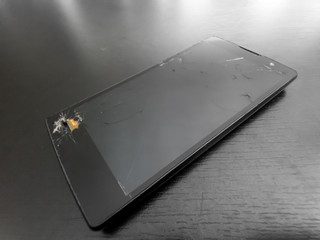 broken phone (cellphone, smartphone or mobilephone) on dark background