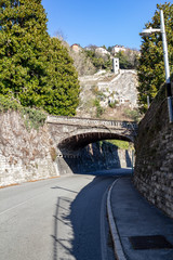 Old pedestrian arch over the highway against the backdrop of Cernobbio Castle, noon. Italy.