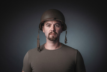 Portrait of a man in a t-shirt wearing a soldier's military helmet,